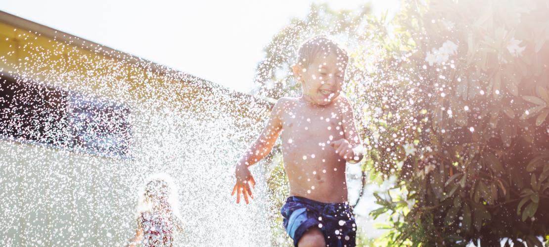 Children running through sprinkler