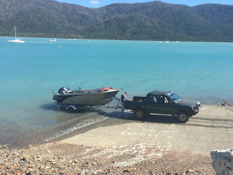 Man hitching boat to ute at boat ramp